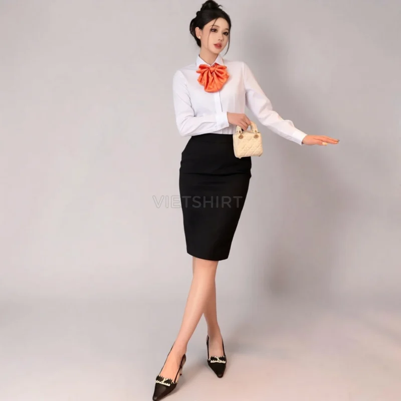 Người mẫu mặc áo sơ mi đồng phục VIB màu trắng với nơ cam, quần đen ngắn